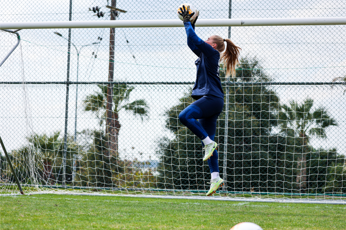 Finnish football player Milla Majasaari catches the ball in front of the goal post.