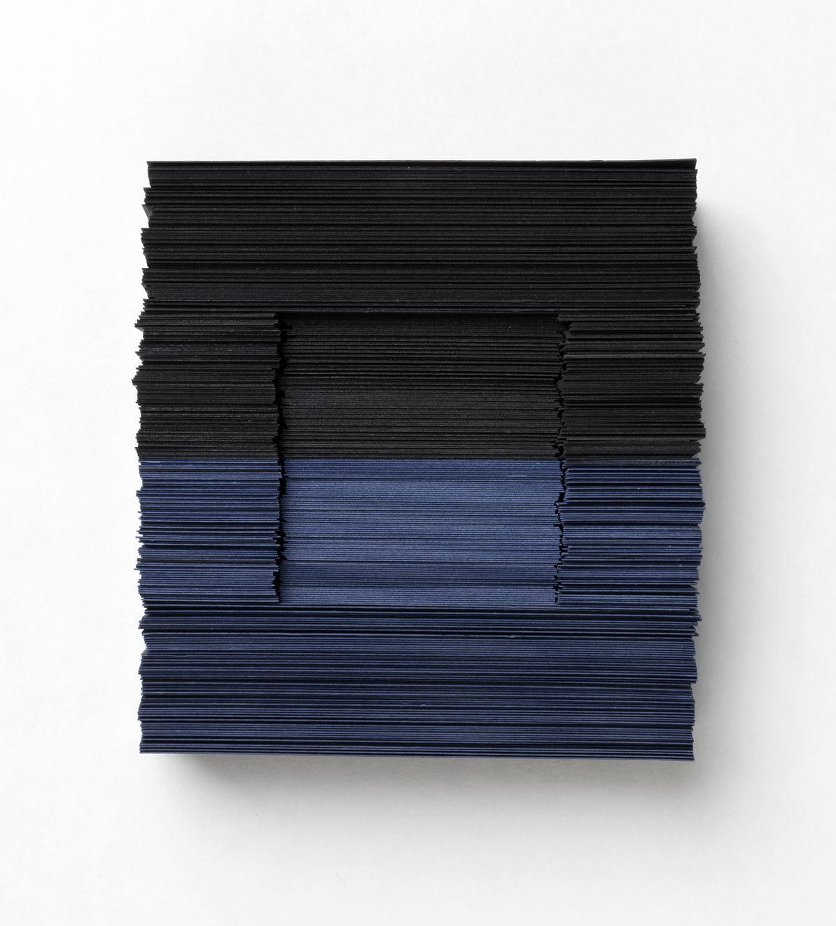 A paper sculpture. The paper gradually shifts from very dark blues to light blues and darker again.