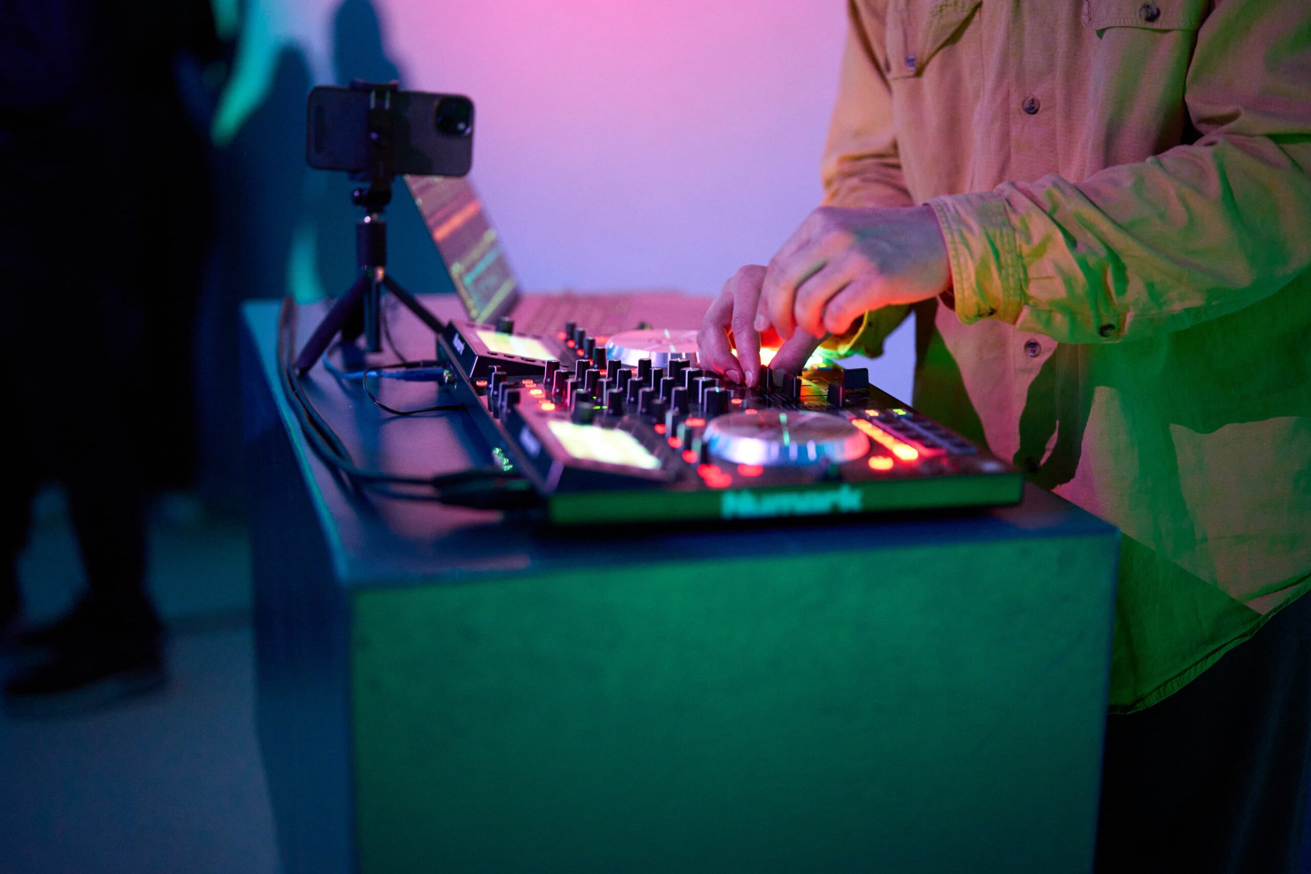 The hands of someone in a yellow shirt can be seen pushing buttons on a mixdesk.